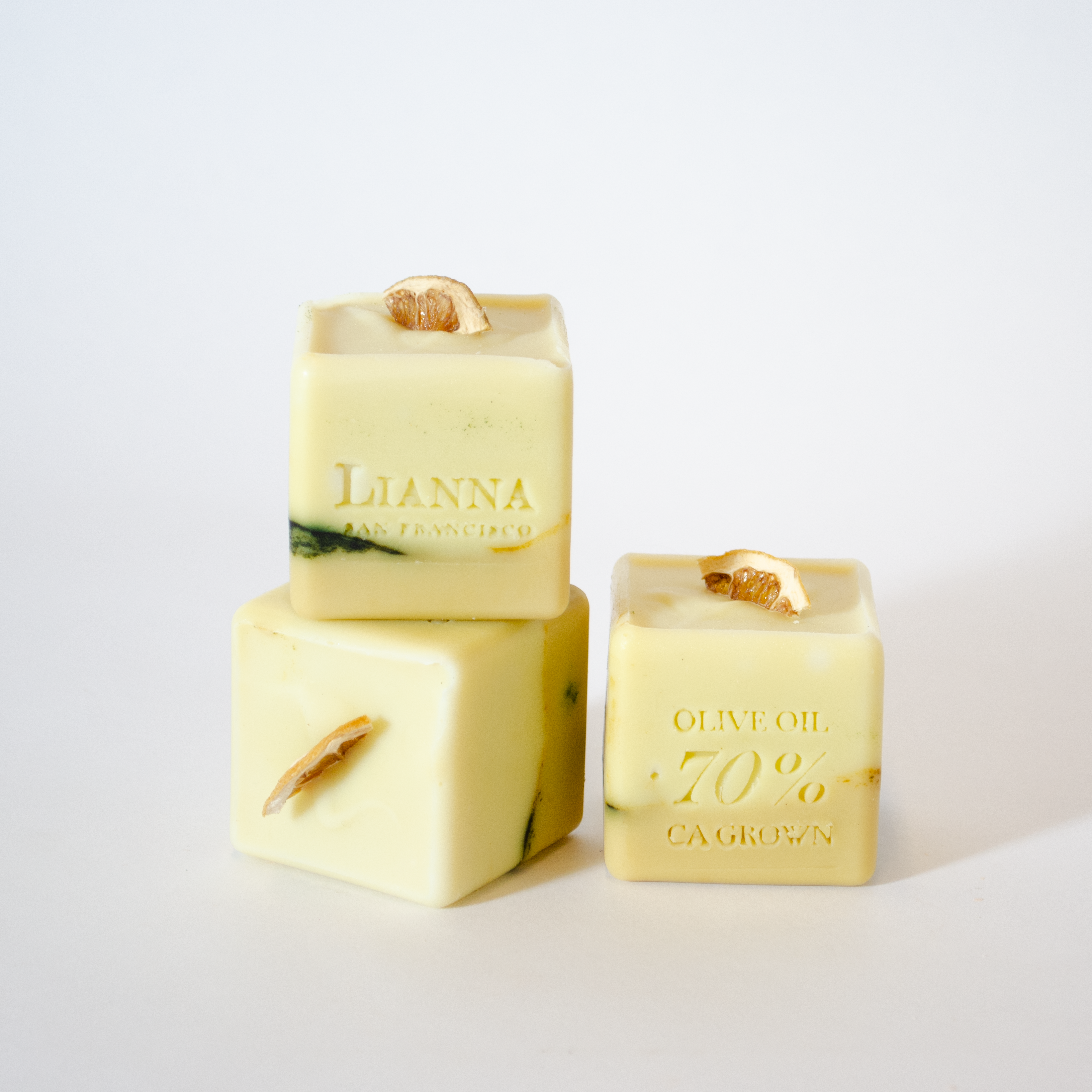 California olive oil soap in the shape of a cube with dehydrated lime wedges nestled on the top that are half white and half green/tan.