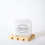 Lade das Bild in den Galerie-Viewer, Bar of winter night olive oil soap wrapped in tree free biodegradable paper packaging. Packaging reads Lianna, all natural soap.
